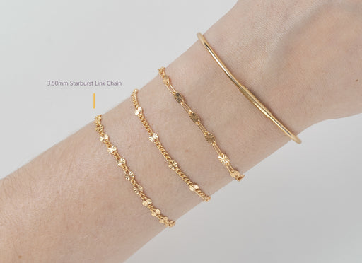 Gold bracelet and chain on a wrist against a light gray background