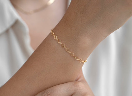 Gold chain on a wrist with a blurred white background