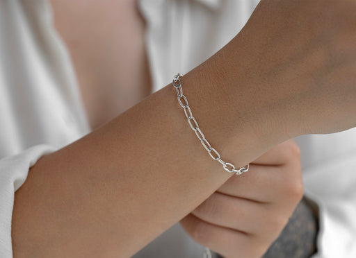 Silver chain bracelet on a wrist with a neutral background