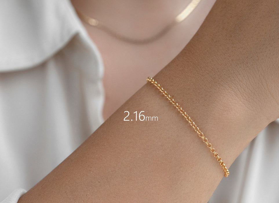 Gold bracelet on a wrist with a white shirt background