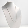 Silver necklace on a mannequin bust against a white background