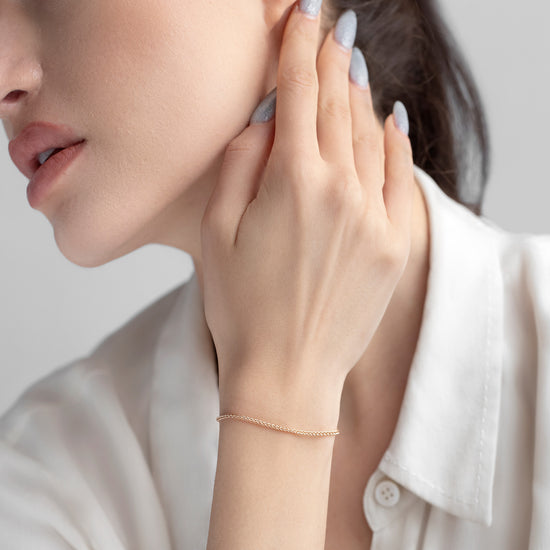 Woman adjusting an earring with a plain background