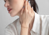 Woman adjusting an earring with a plain background