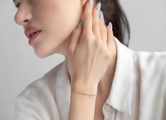 Woman adjusting an earring with a plain background