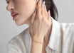 Woman adjusting an earring with a plain background