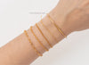 Gold bracelets on a wrist with a plain background