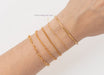 Gold bracelets on a wrist with a plain background