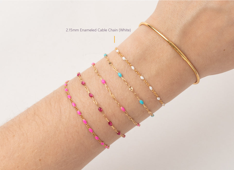 Gold bracelet with pink and blue beads on a wrist against a white background