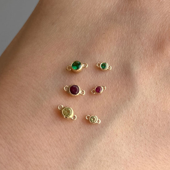 Gold jewelry charms with gemstones on a skin background