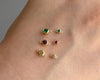 Gold jewelry charms with gemstones on a skin background