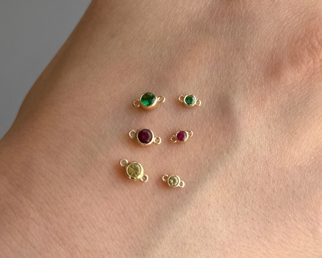 Gold jewelry charms with gemstones on a skin background
