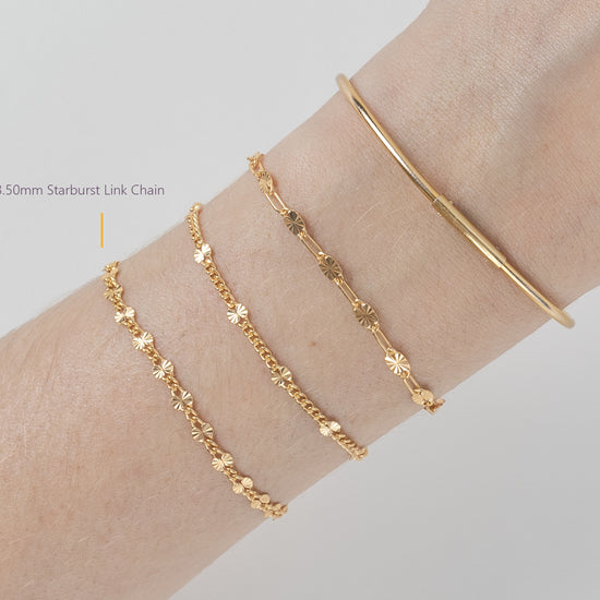 Gold bracelet and chain on a wrist against a light gray background