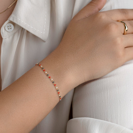 Hand wearing a bracelet and ring on a neutral background