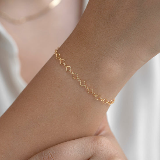 Gold chain on a wrist with a blurred white background