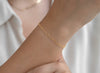 Gold chain on a wrist with a blurred white background