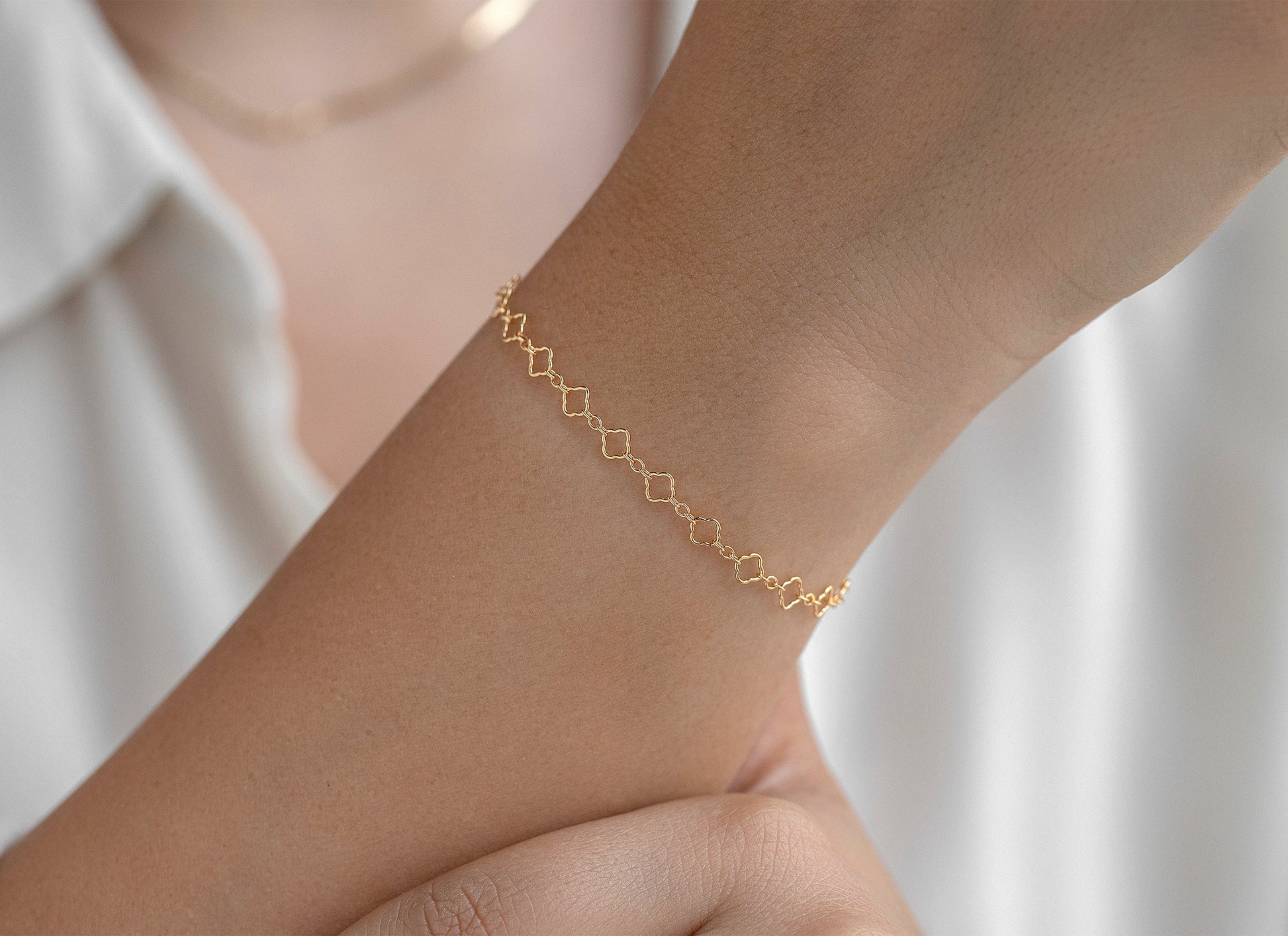 Gold chain on a wrist with a blurred white background