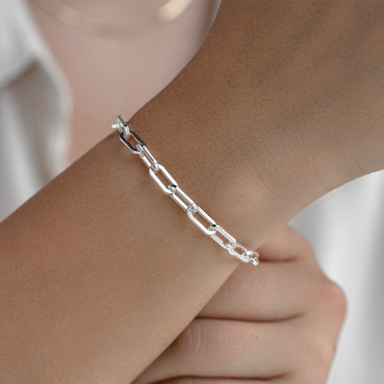 Silver 5mm chain bracelet on a wrist with a blurred background