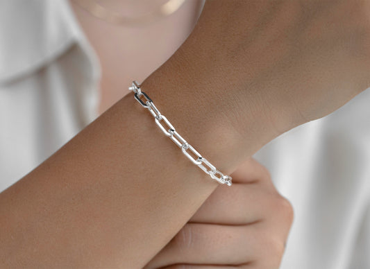 Silver 5mm chain bracelet on a wrist with a blurred background