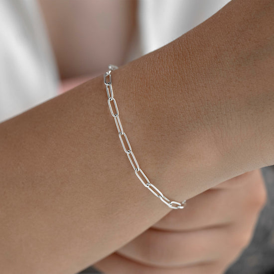 Silver chain bracelet on a wrist with a neutral background