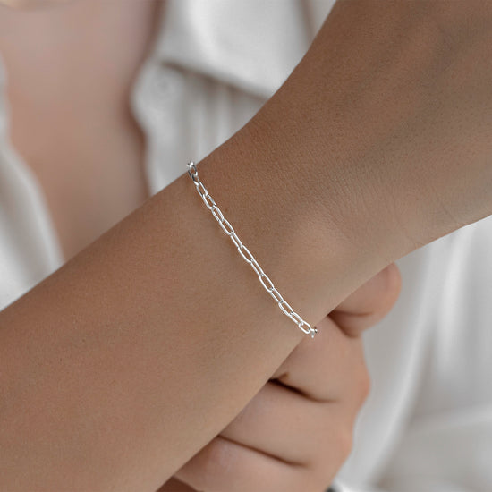 Silver bracelet on a wrist with a neutral background