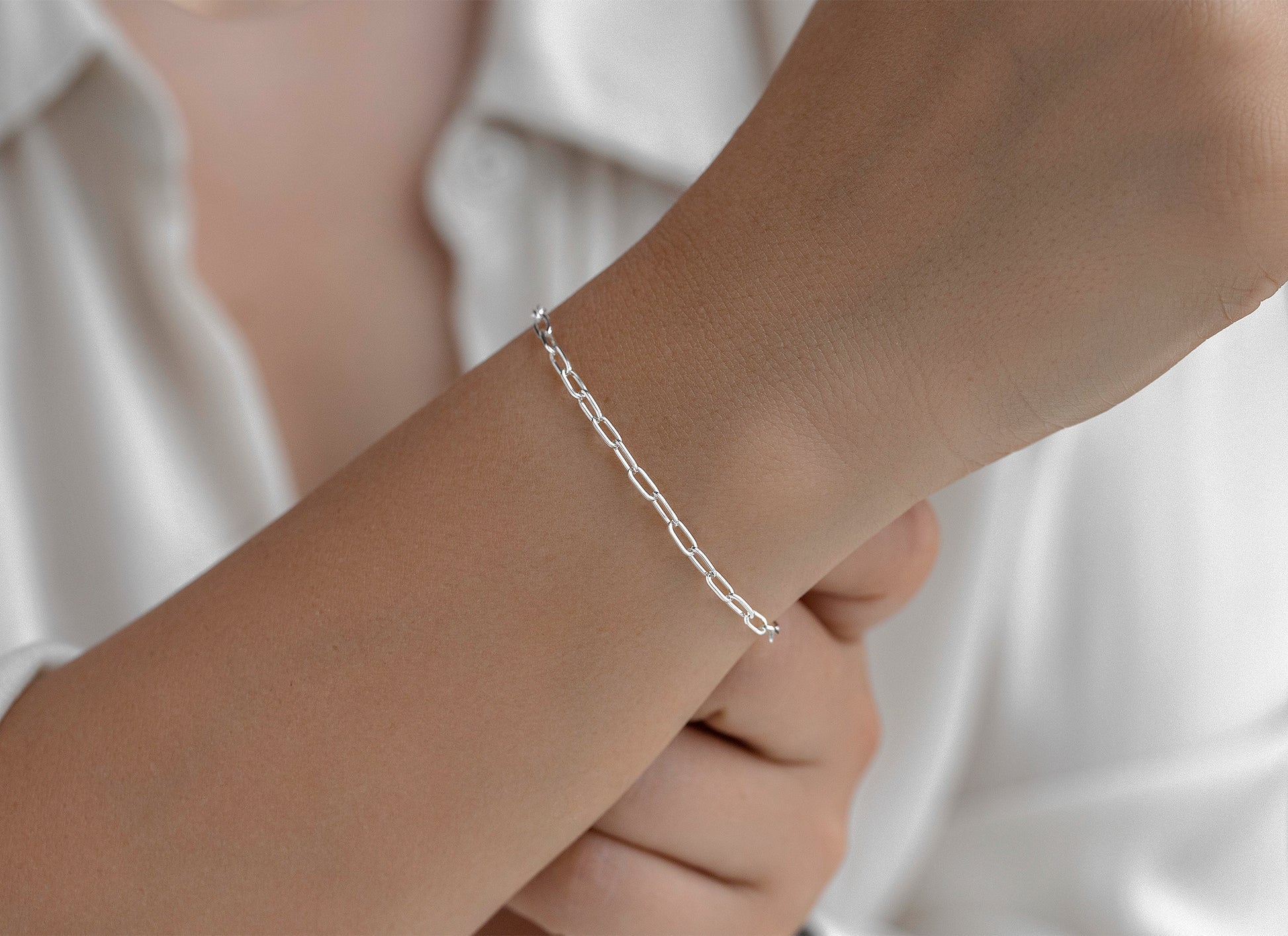 Silver bracelet on a wrist with a neutral background