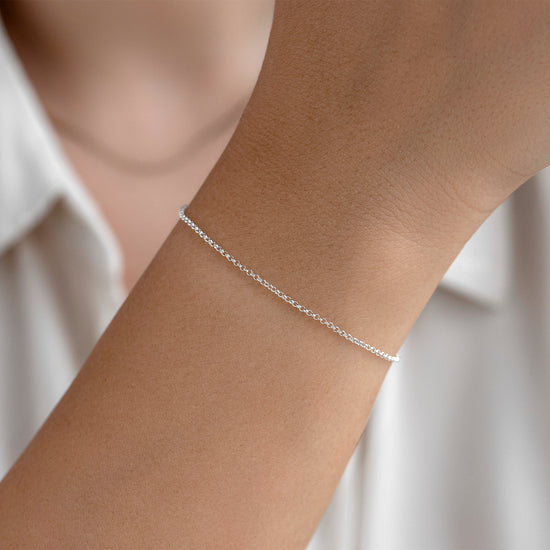 Silver bracelet on a person's wrist against a white background