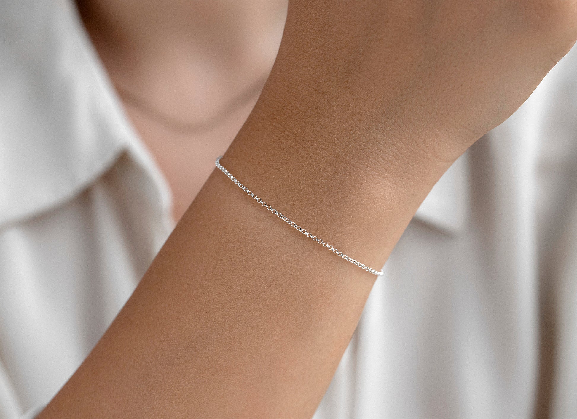 Silver bracelet on a person's wrist against a white background