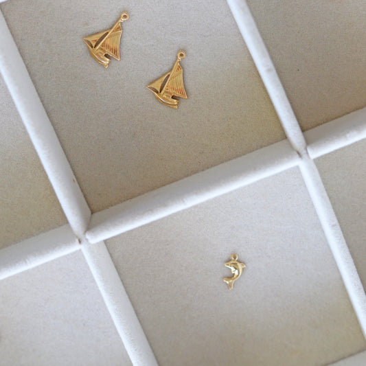 Gold sailboat-shaped earrings on a grid-patterned surface