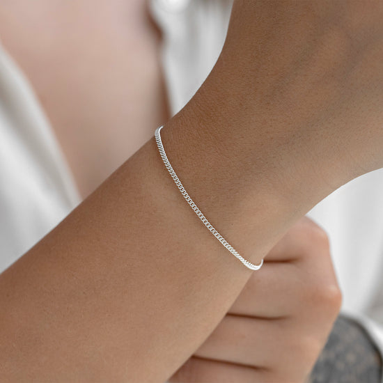 Silver bracelet on a person's wrist with a plain background