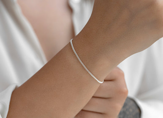 Silver bracelet on a person's wrist with a plain background