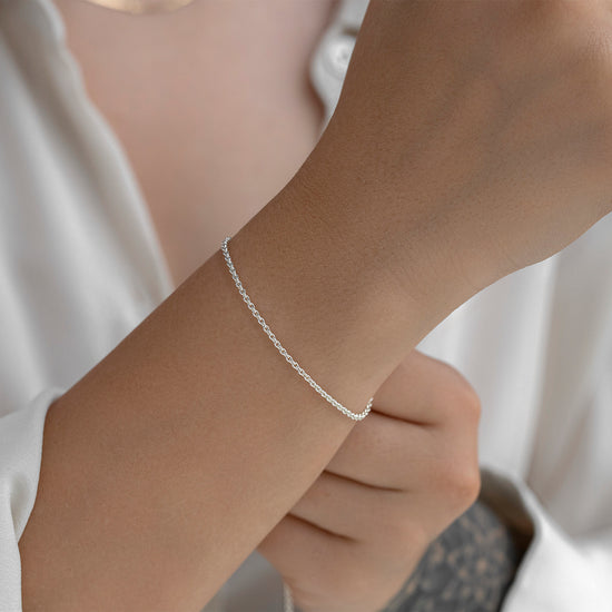 Silver bracelet on a wrist with a neutral background