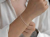 Silver bracelet on a wrist with a neutral background