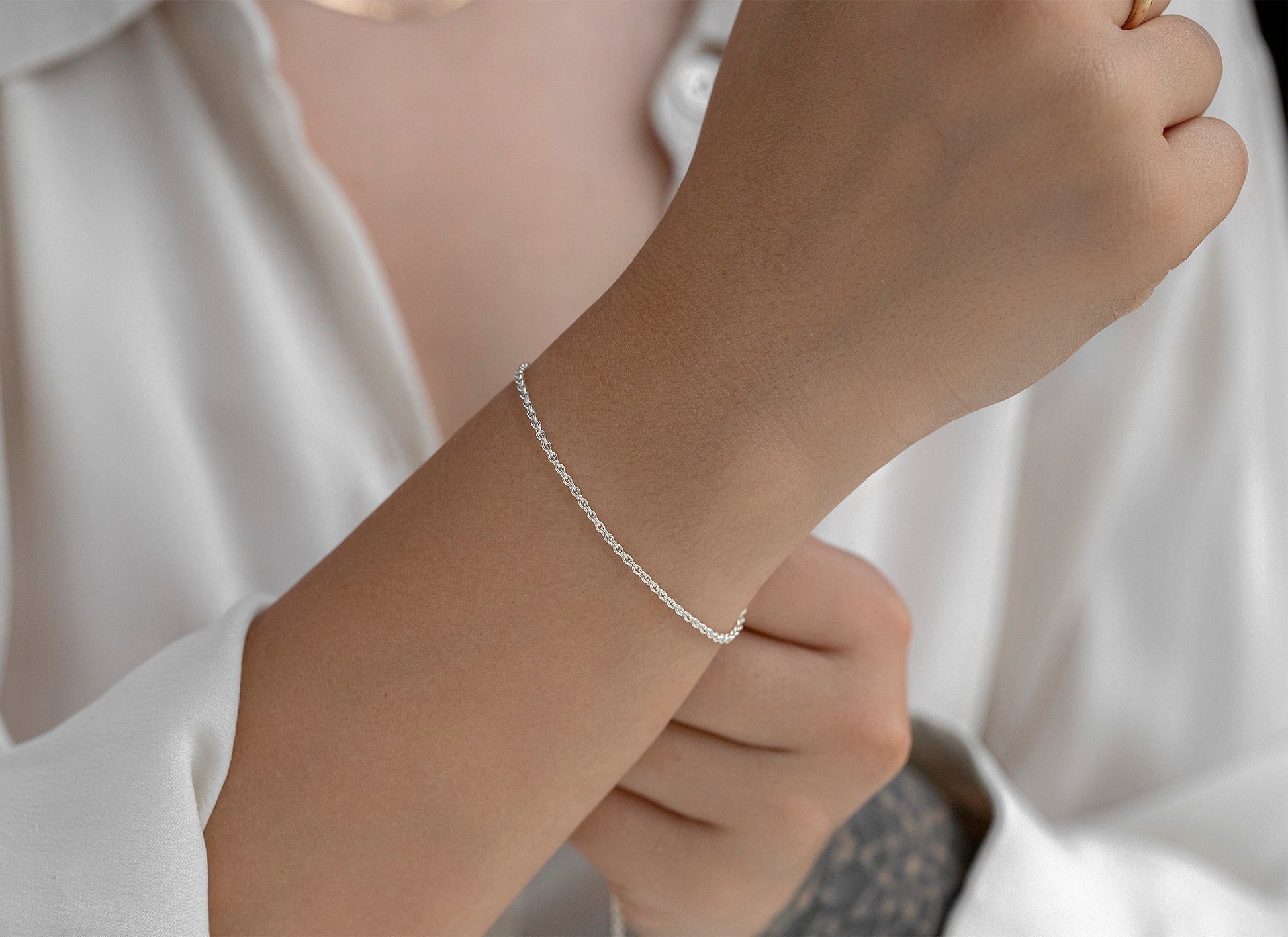 Silver bracelet on a wrist with a neutral background