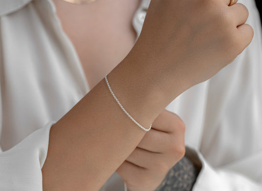 Silver bracelet on a wrist with a neutral background