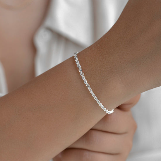 Silver rolo bracelet on a person's wrist with a blurred background
