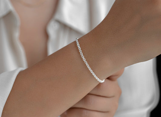 Silver rolo bracelet on a person's wrist with a blurred background