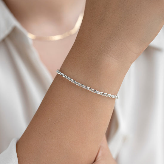 Silver bracelet on a person's wrist with a blurred white shirt background