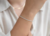 Silver bracelet on a person's wrist with a blurred white shirt background