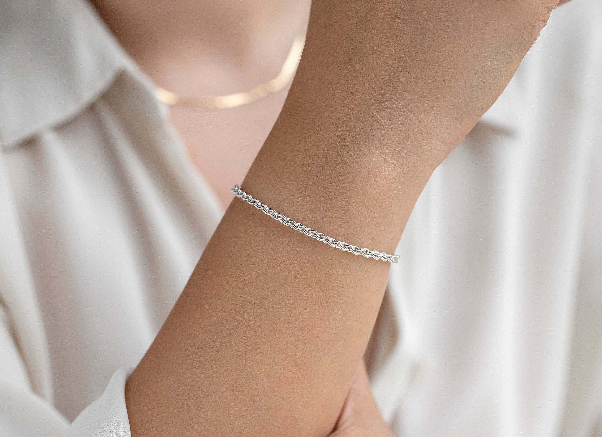 Silver bracelet on a person's wrist with a blurred white shirt background