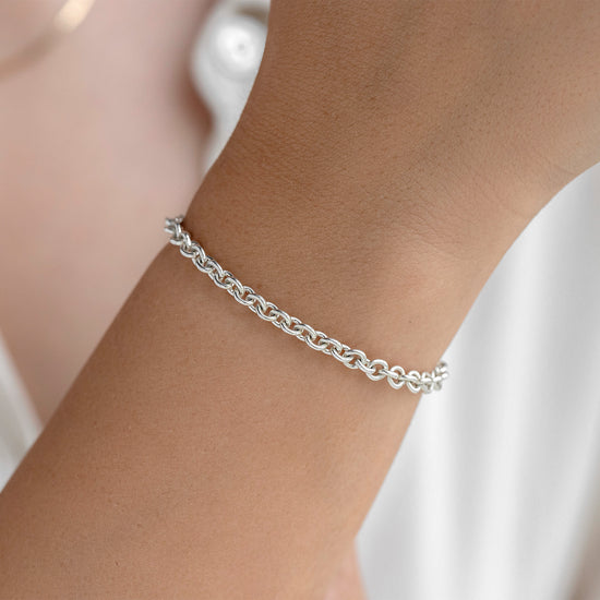 Silver chain bracelet on a wrist with a white background