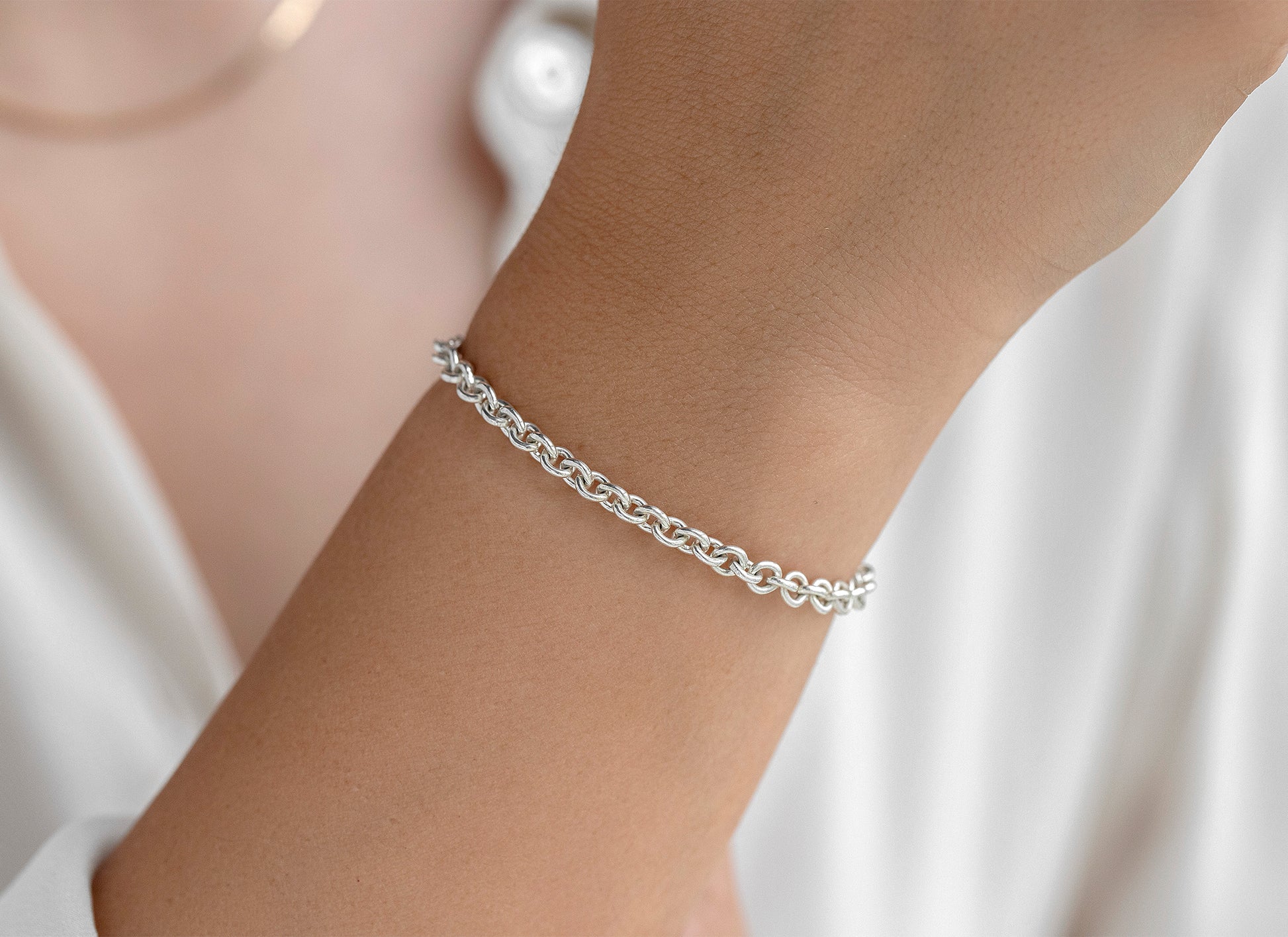 Silver chain bracelet on a wrist with a white background