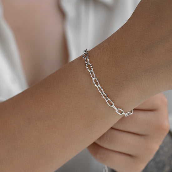 Silver chain bracelet on a wrist with a neutral background