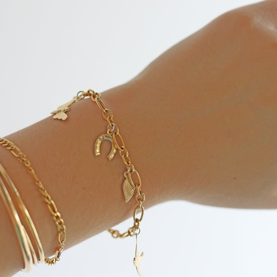 Gold bracelets on a wrist against a white background