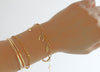Gold bracelets on a wrist against a white background
