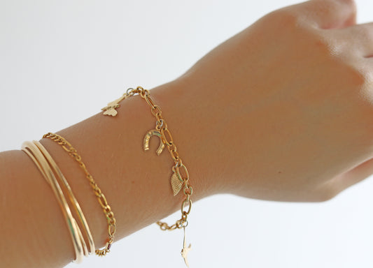 Gold bracelets on a wrist against a white background