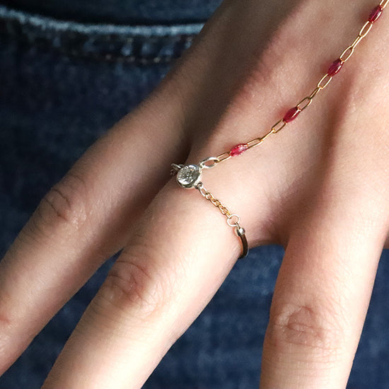 Hand wearing a gold bracelet with red stones against a dark background