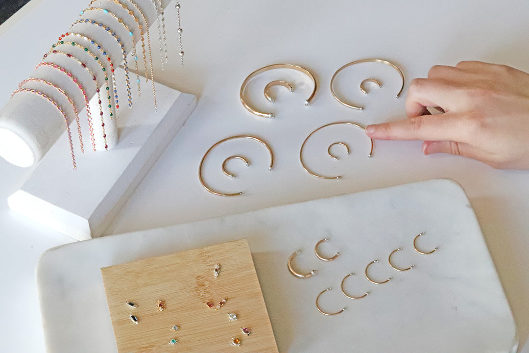 Gold permanent rings displayed on a white surface with a hand reaching out.