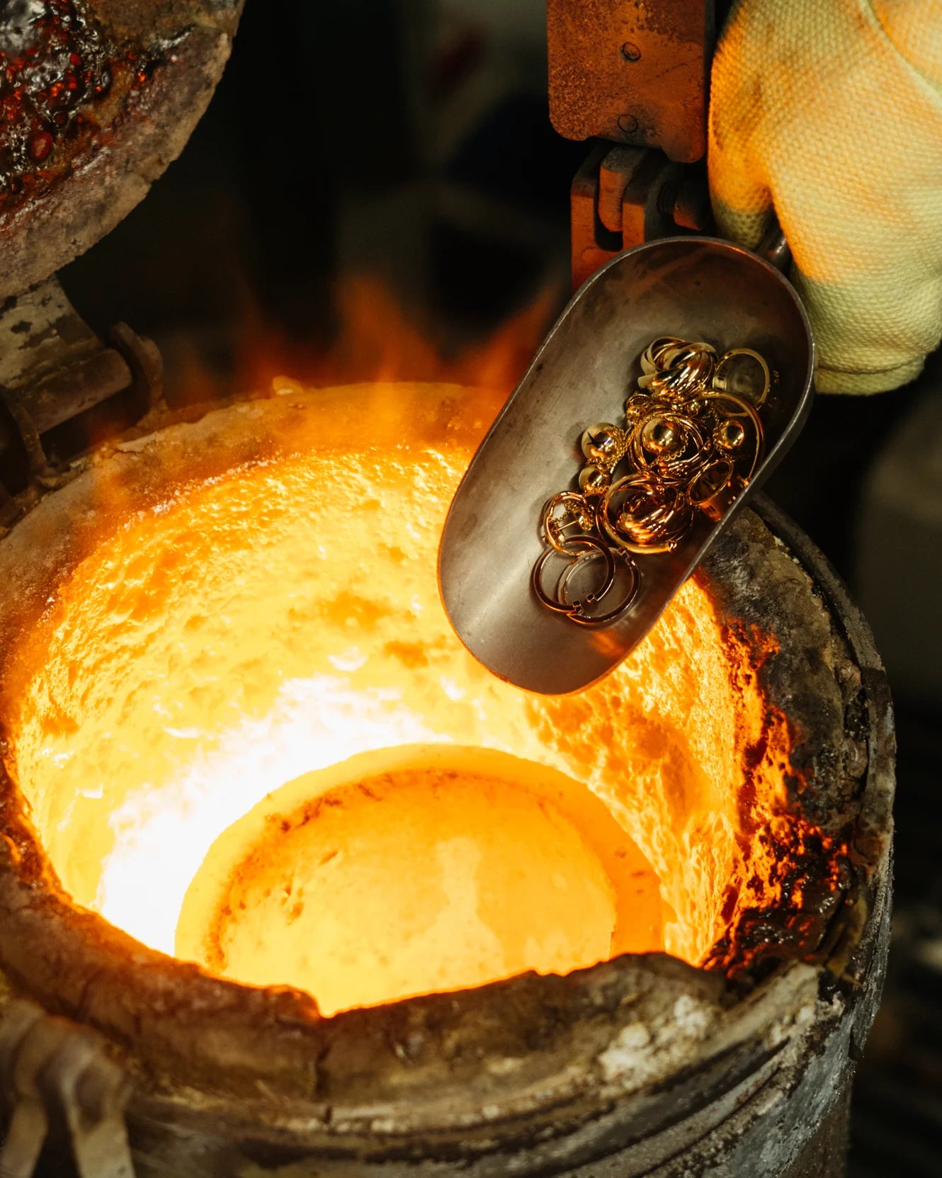 Gold jewelry being melted within a furnace with flames and glowing metal.