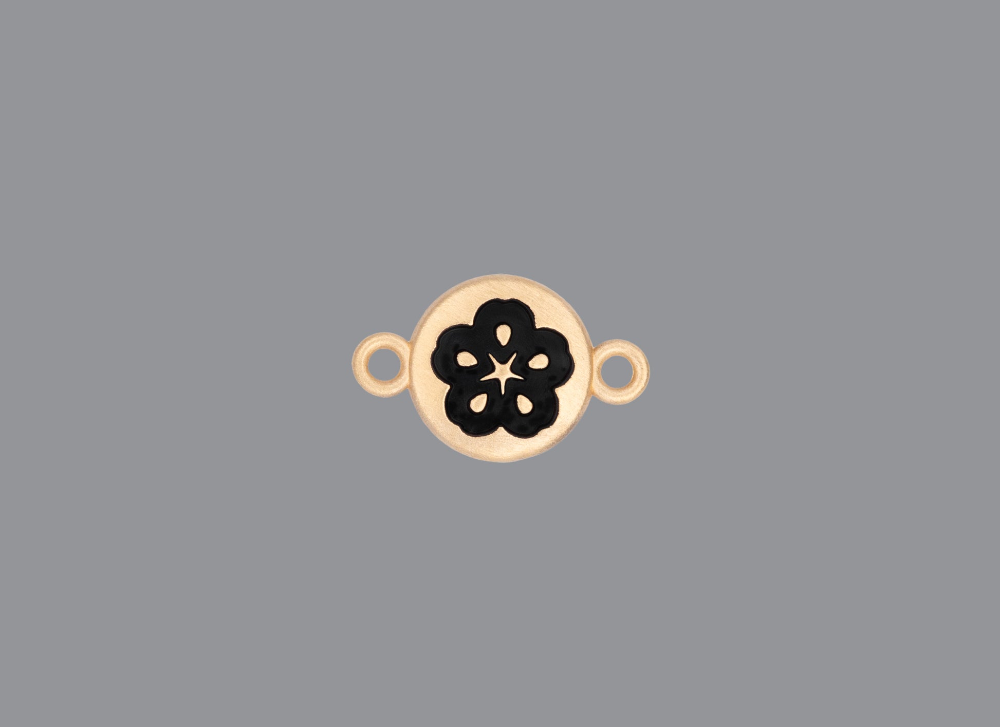 Round emoji connector in gold with a flower engraving on gray background