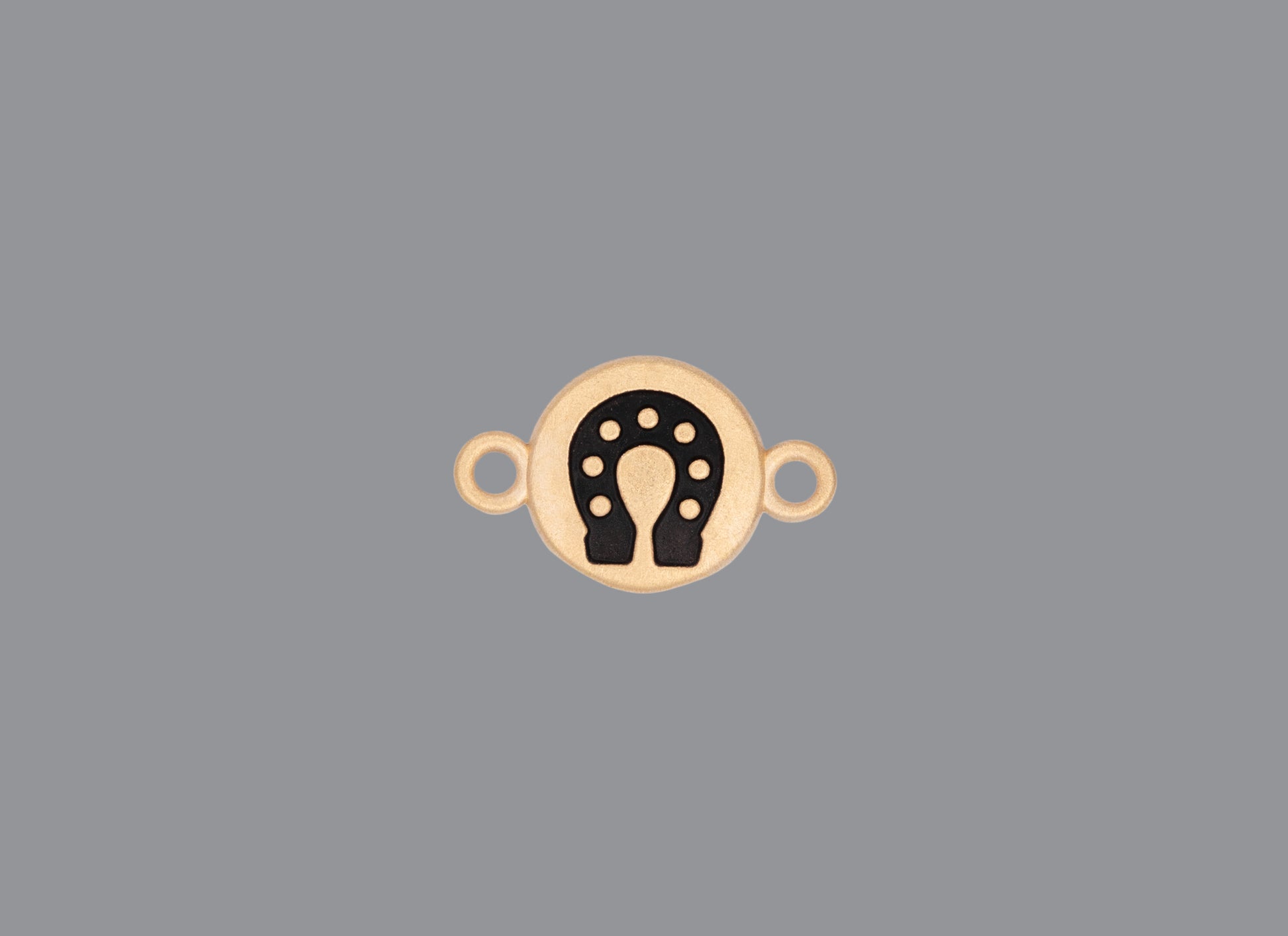 Round emoji connector in gold with a horseshoe engraving on gray background